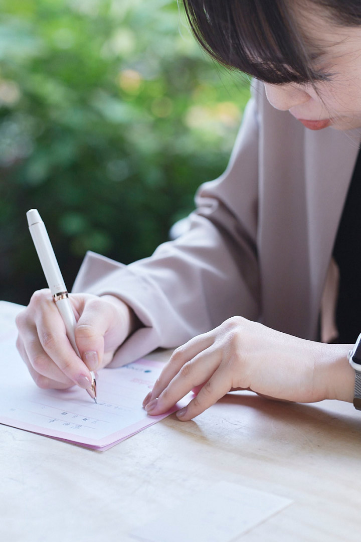 女性がノートに文字を書いている